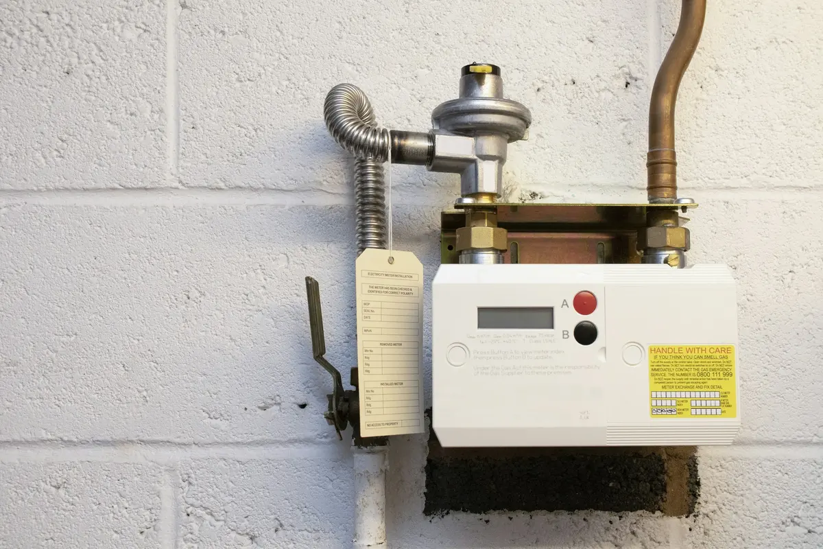 A domestic gas meter and regulator on a painted wall