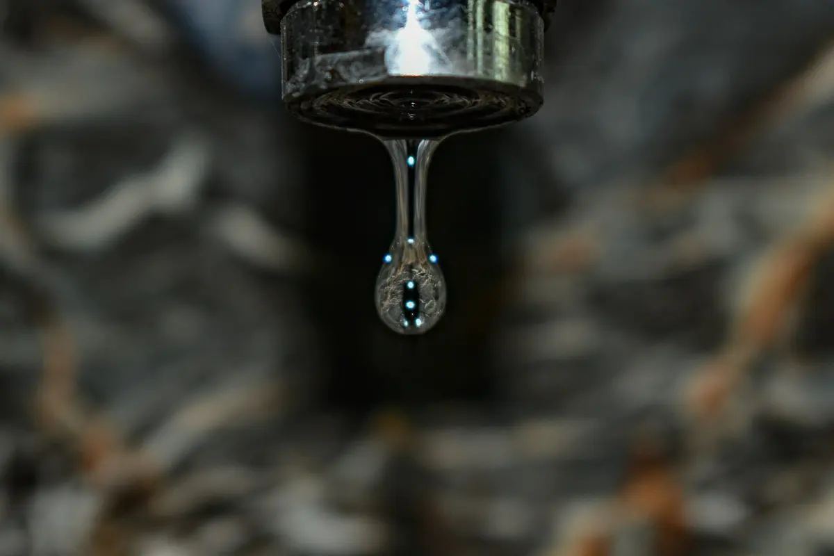 A drop of water falling from a tap, dark background